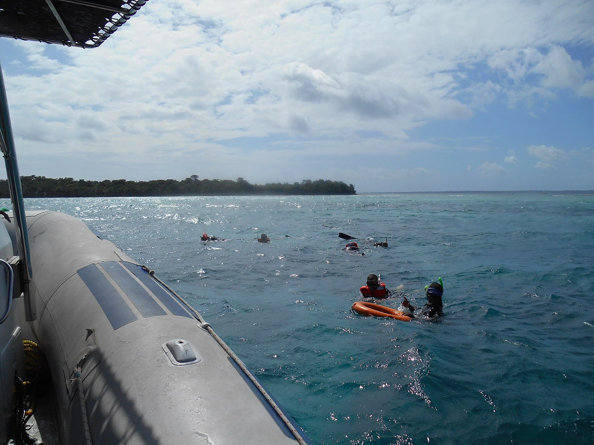 Snorkellers in open water beside a boat off Zanzibar's north coast