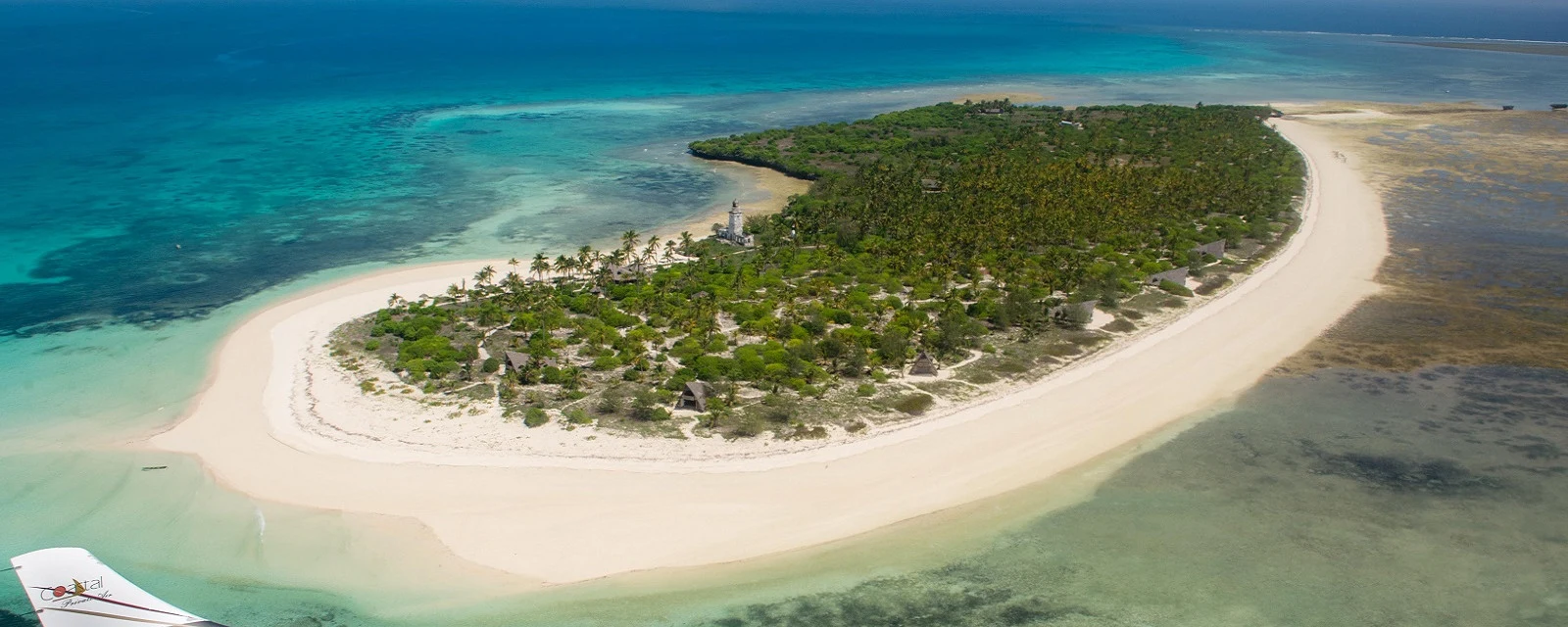 A sandbar island with turquoise reef shallows, seen from the air
