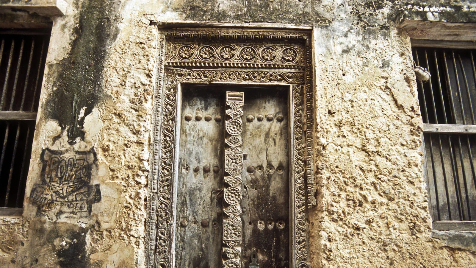 Carved wooden door set in weathered coral stone wall