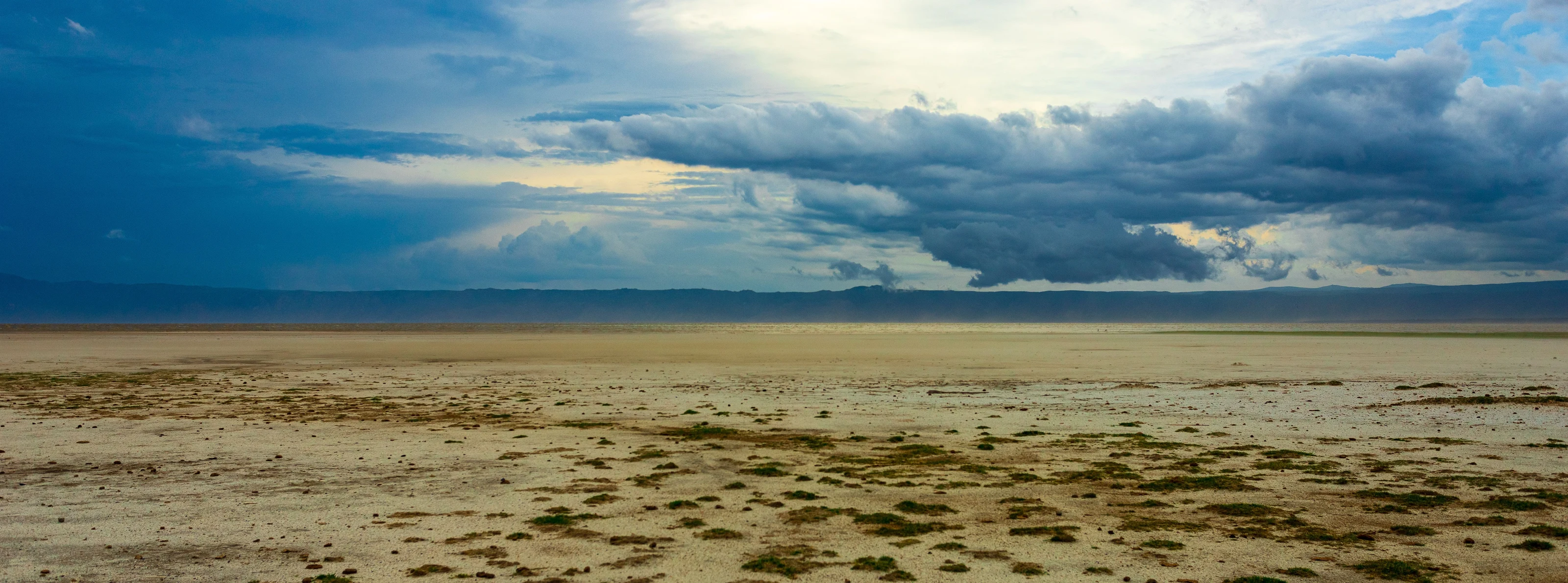 The dry lakebed of Lake Eyasi under a wide cloudy sky