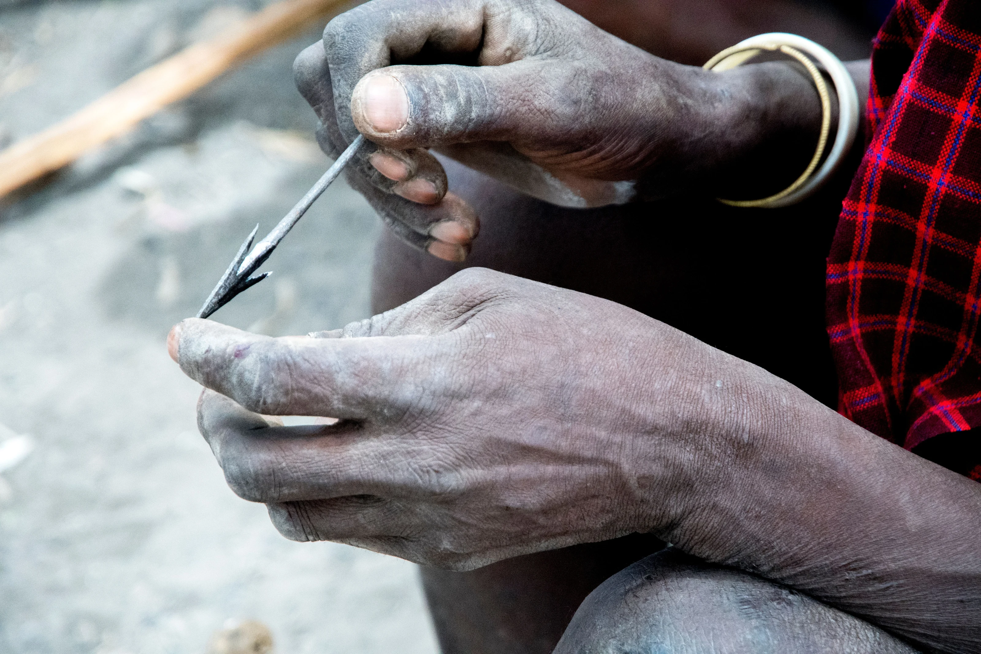 Close view of a Datoga craftsman shaping a metal arrowhead