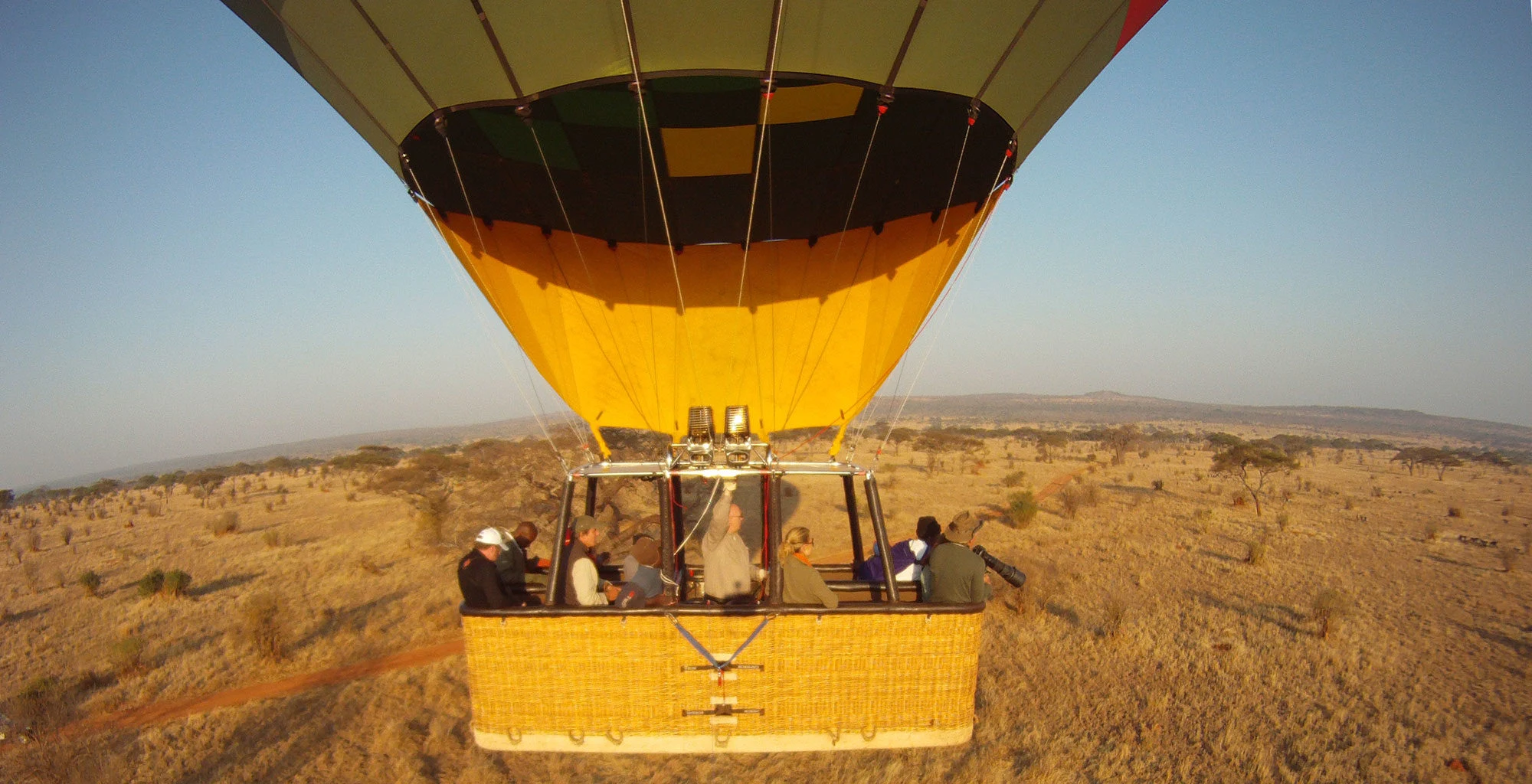 Guests look out from a hot-air-balloon basket above the landscape
