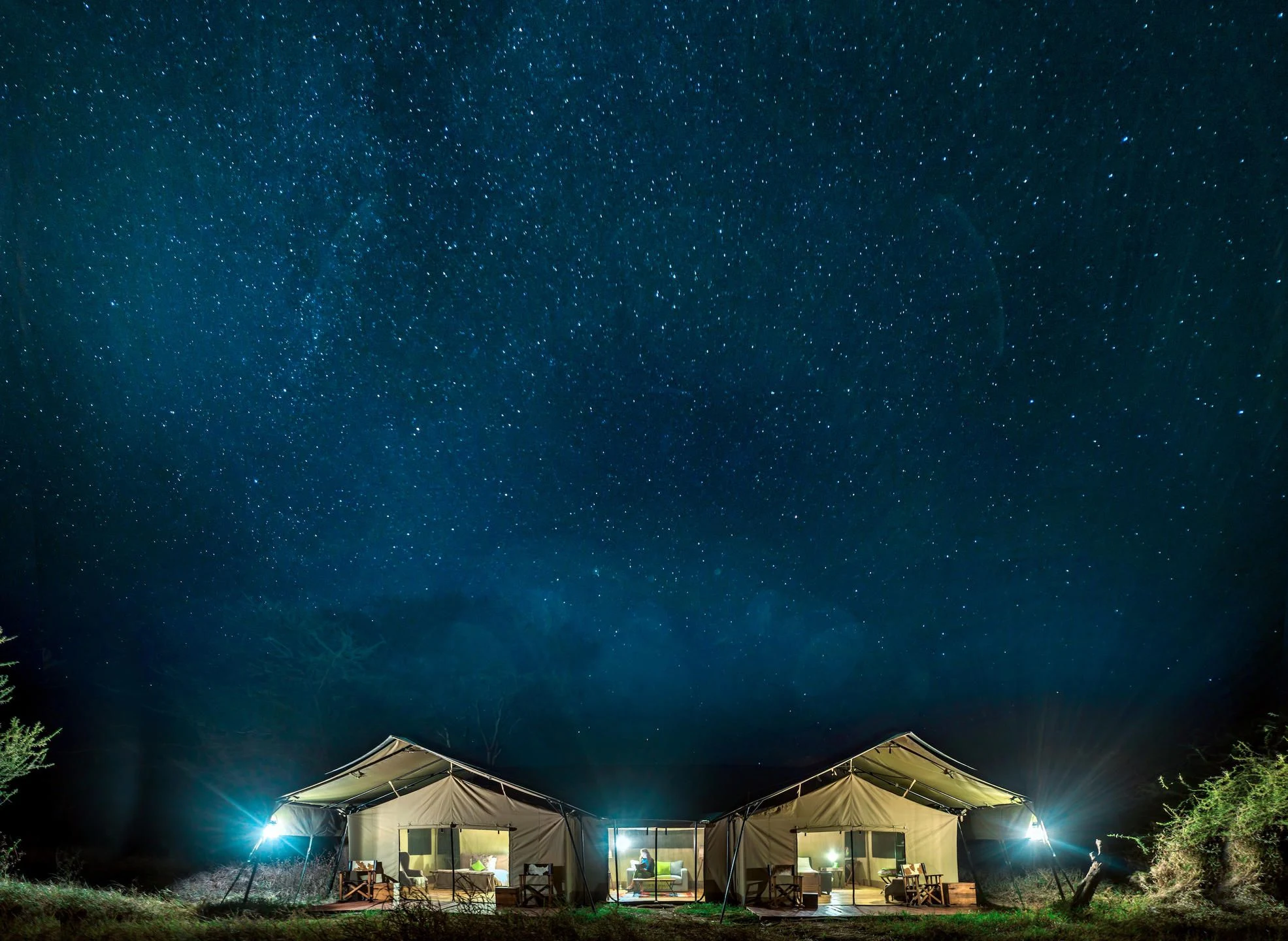 Lit safari tents under a starry night sky in the central Serengeti