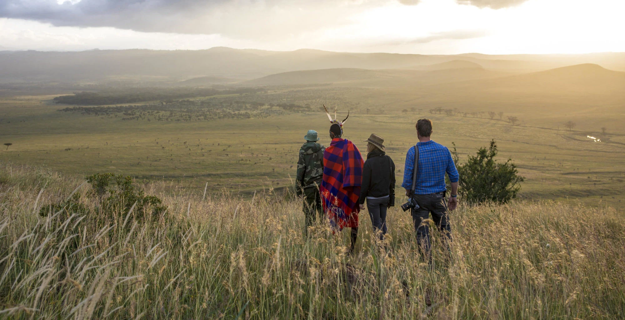 Walkers with a guide crossing open grassland at Lewa