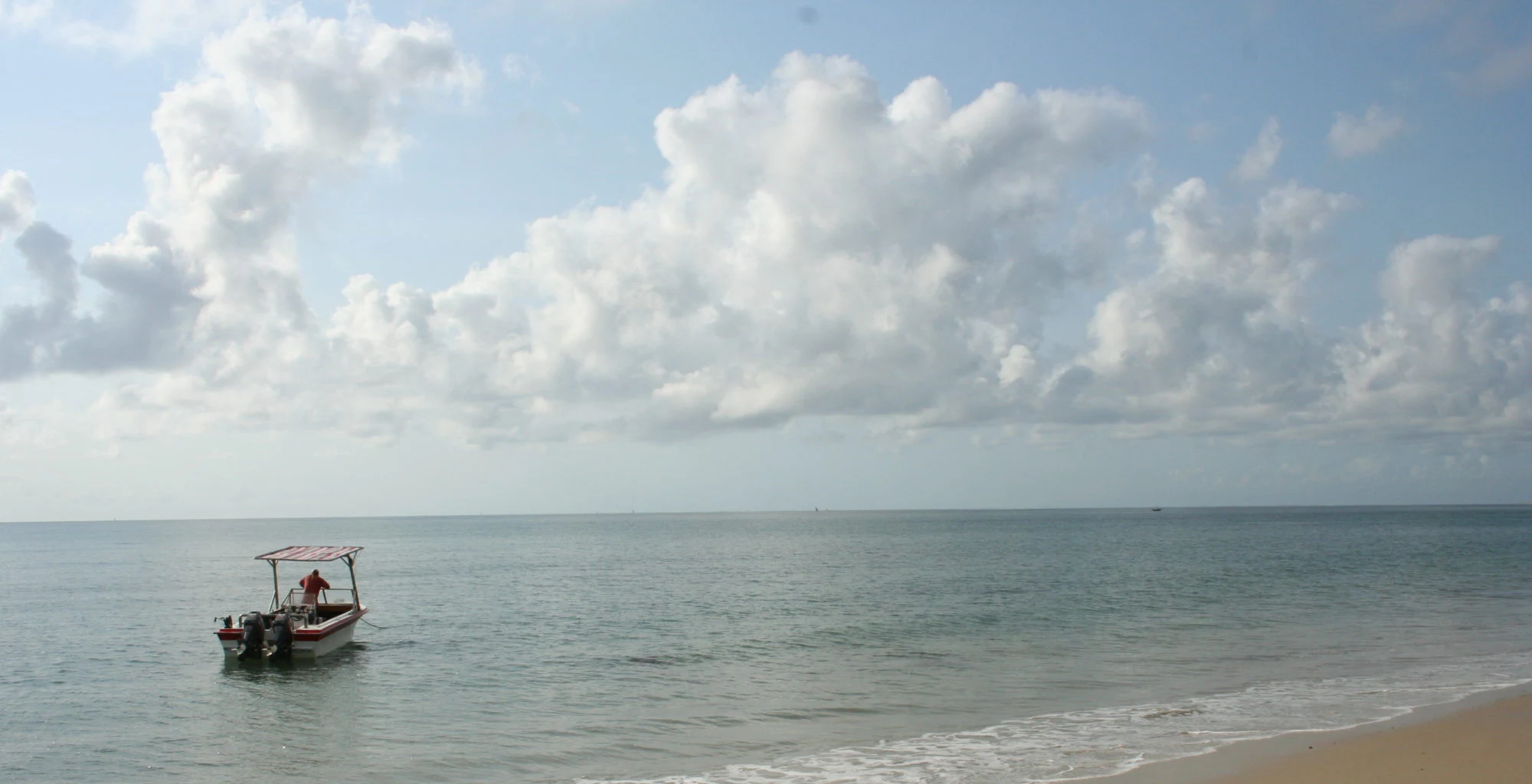 A small fishing boat on calm water off a sandy shore