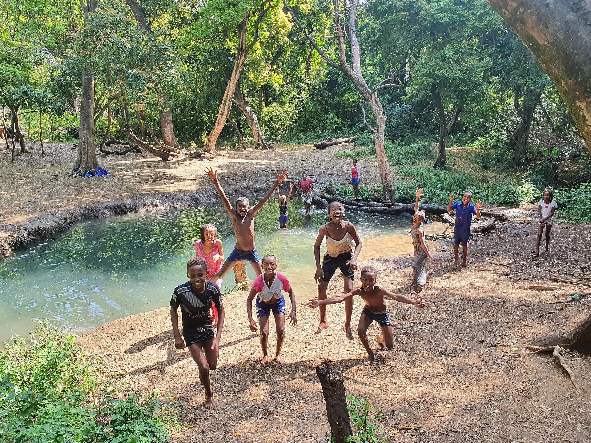 Local boys play beside a clear natural spring pool under trees in Arba Minch.