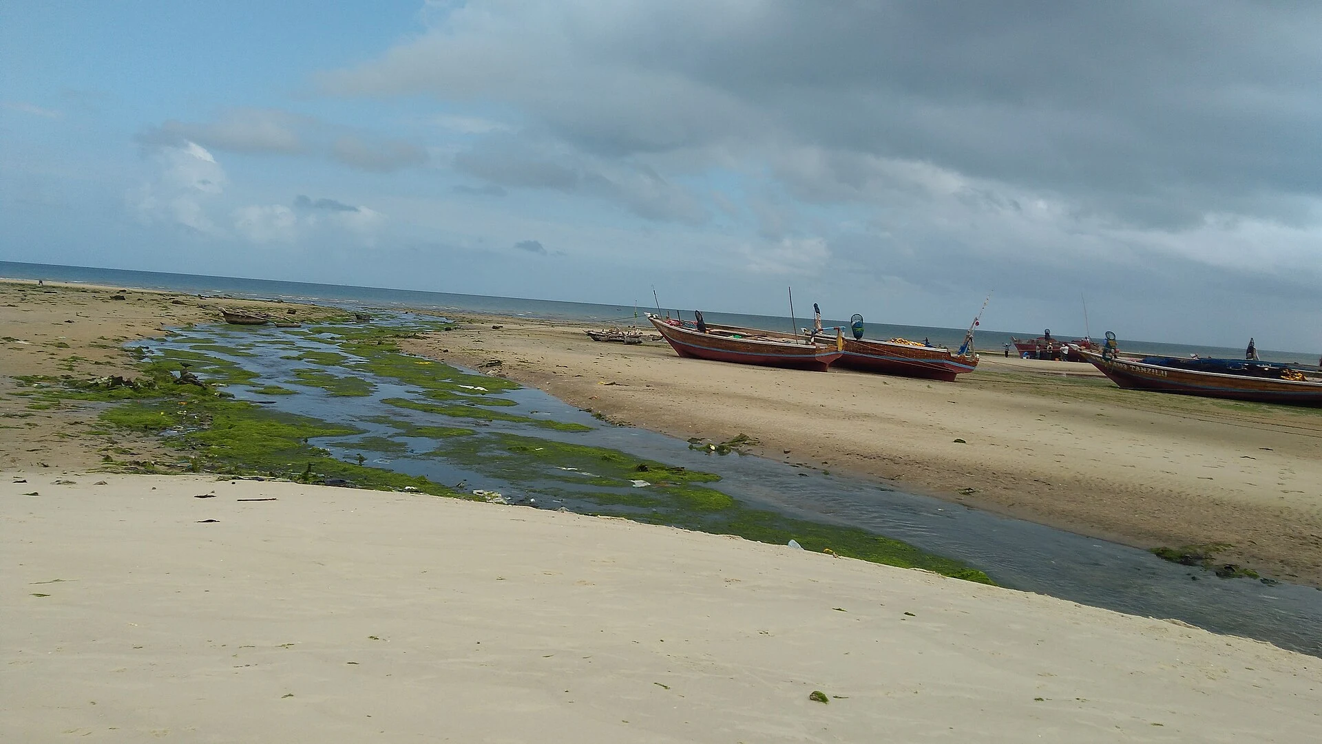 Wooden fishing boats pulled up on a quiet Zanzibar beach at low tide
