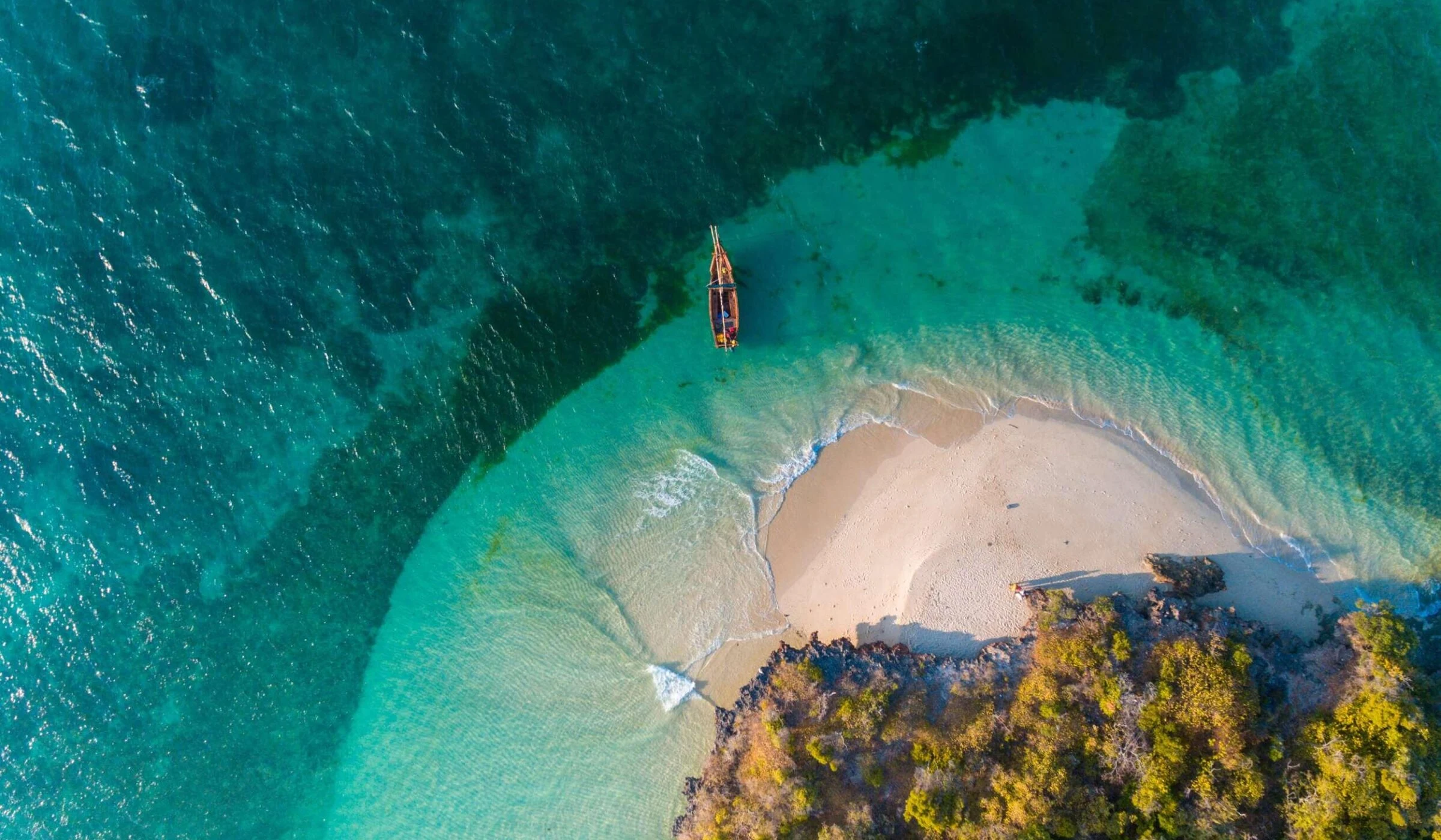 Aerial of a boat off a small white sand cove