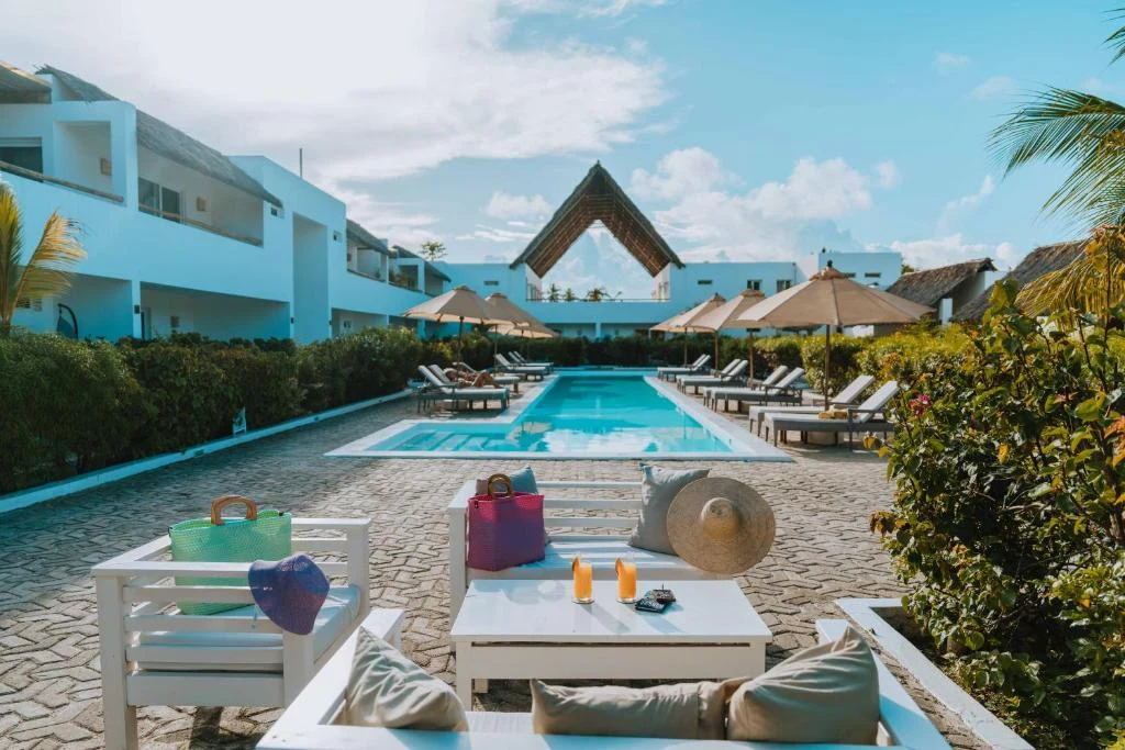 a pool at a resort with lounge chairs and a table at Dhow Inn Boutique Hotel in Paje
