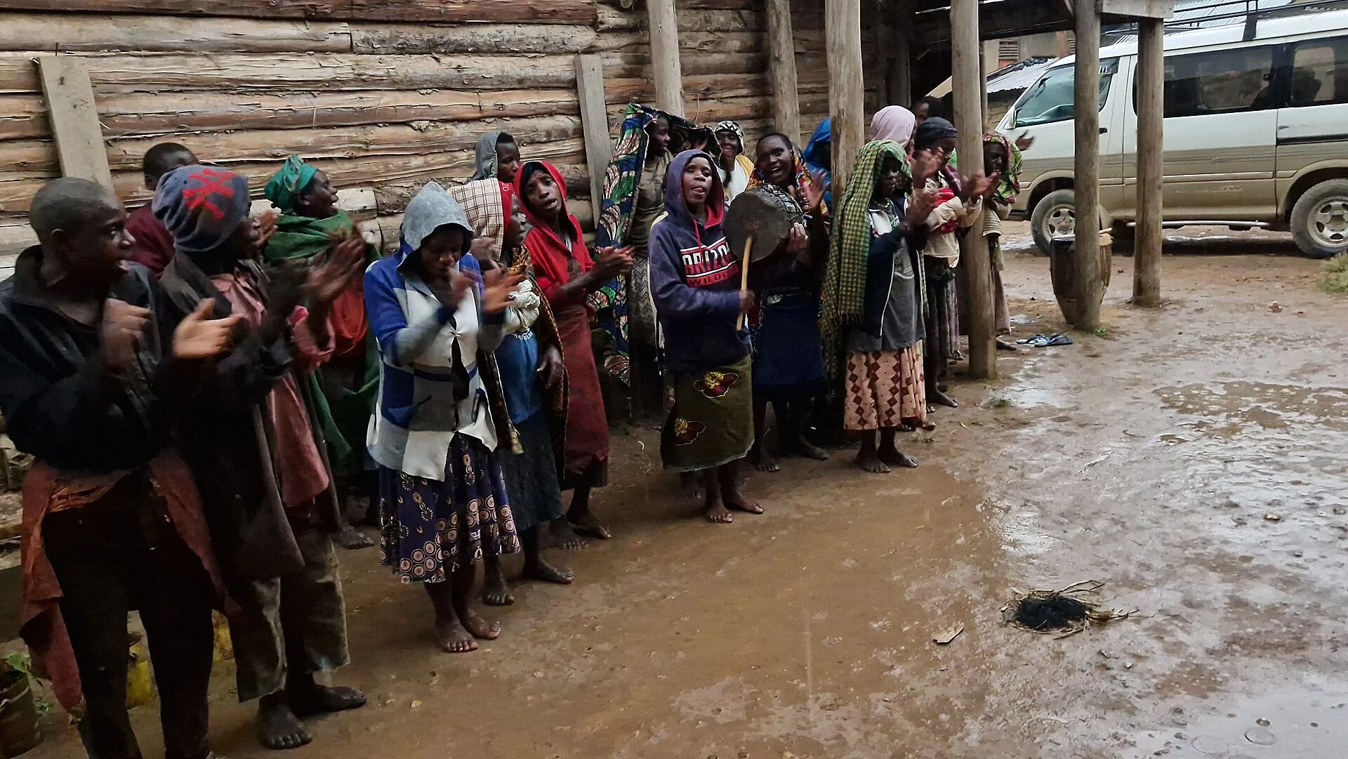 Batwa villagers clapping and dancing outside a tourist centre in Rushaga