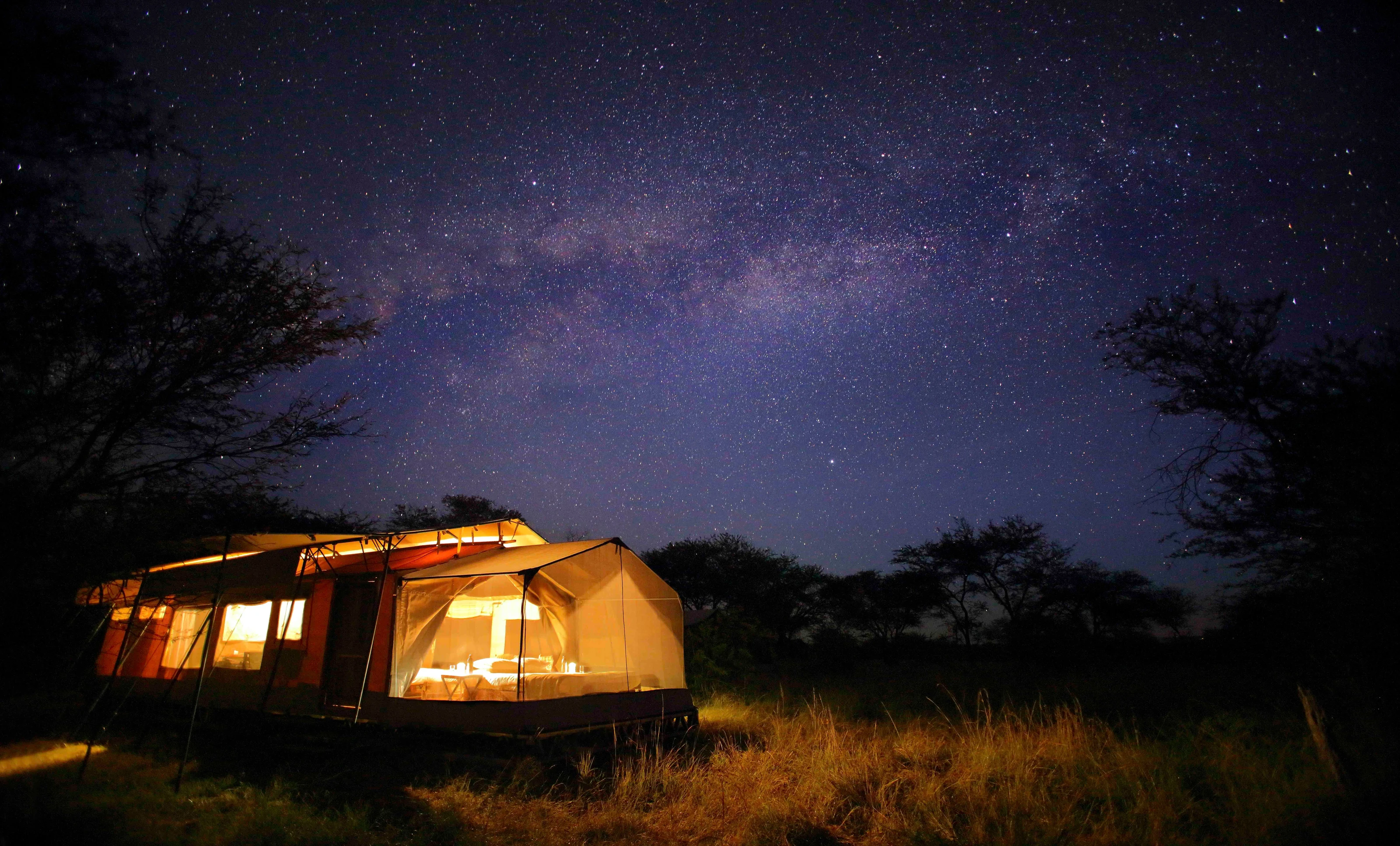 A lit tent under the Milky Way