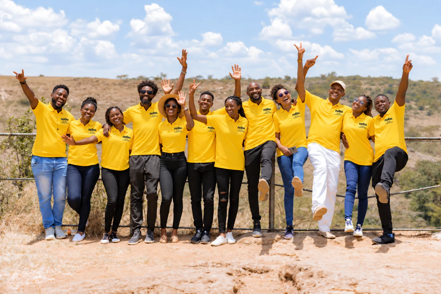 Illustrative group portrait in yellow Nobu Safaris shirts on open grassland