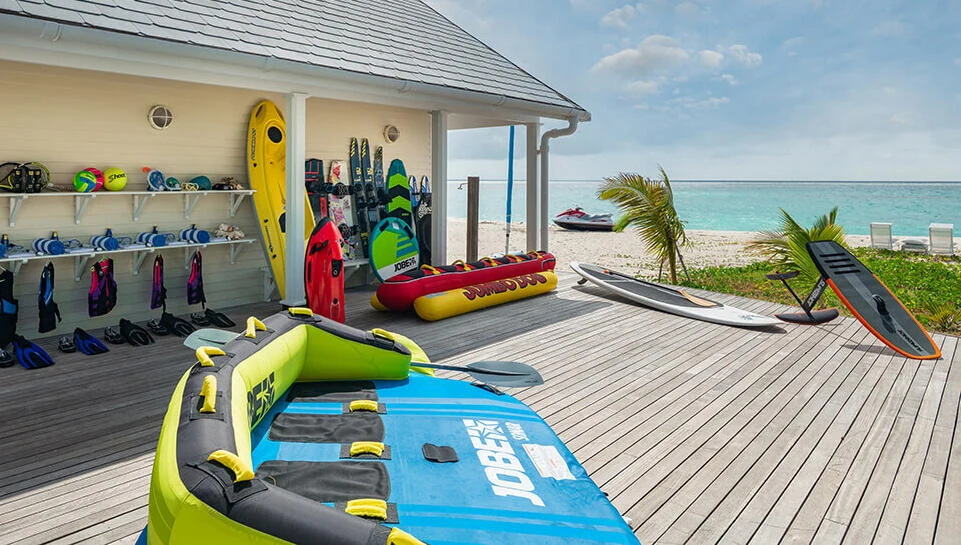 Kayaks, paddleboards and life jackets ready on a beach deck