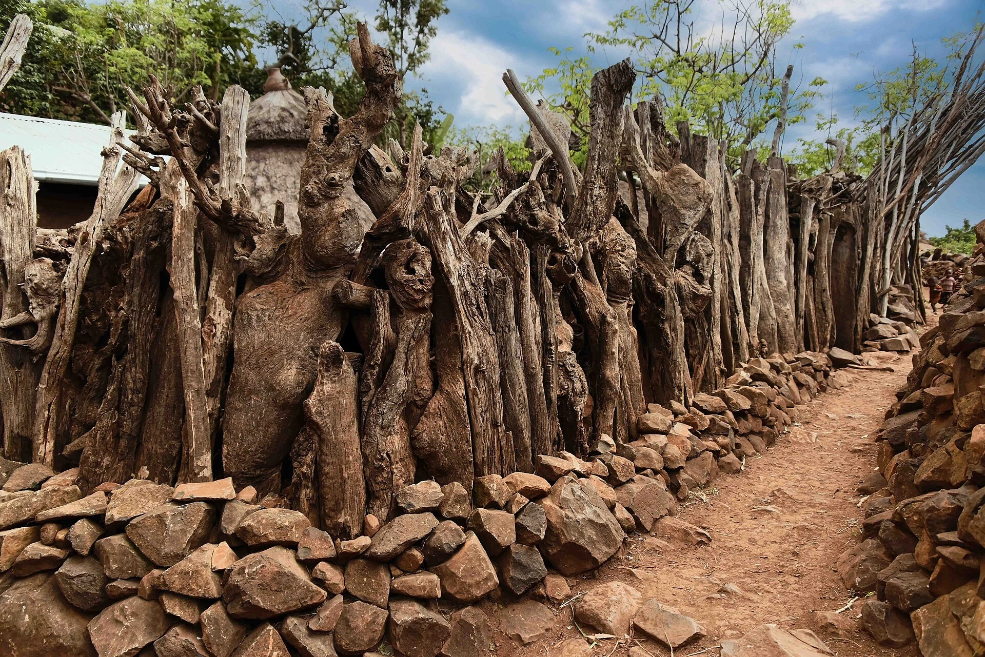 A narrow path runs between stone and timber walls in a walled Konso village.