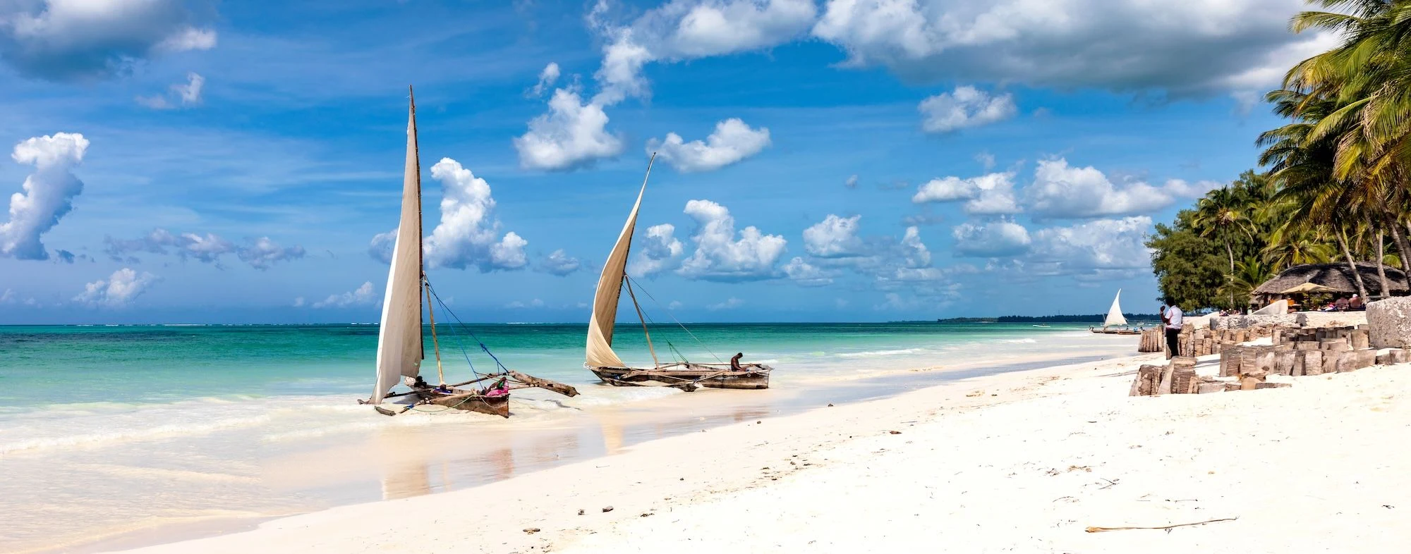 Dhows resting beside a white sand beach and clear shallow sea