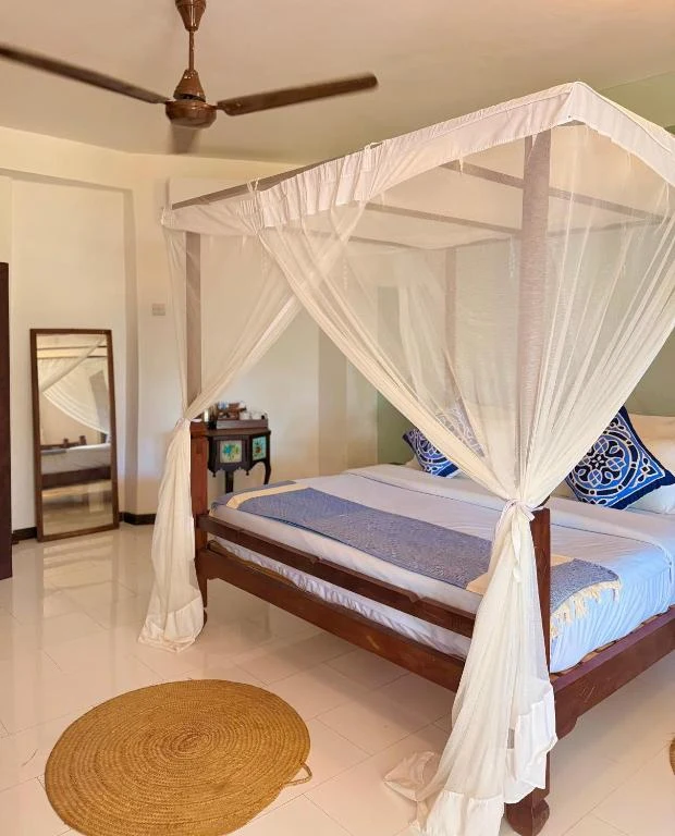 a bedroom with a bed with a canopy at Flame Tree Cottages in Nungwi