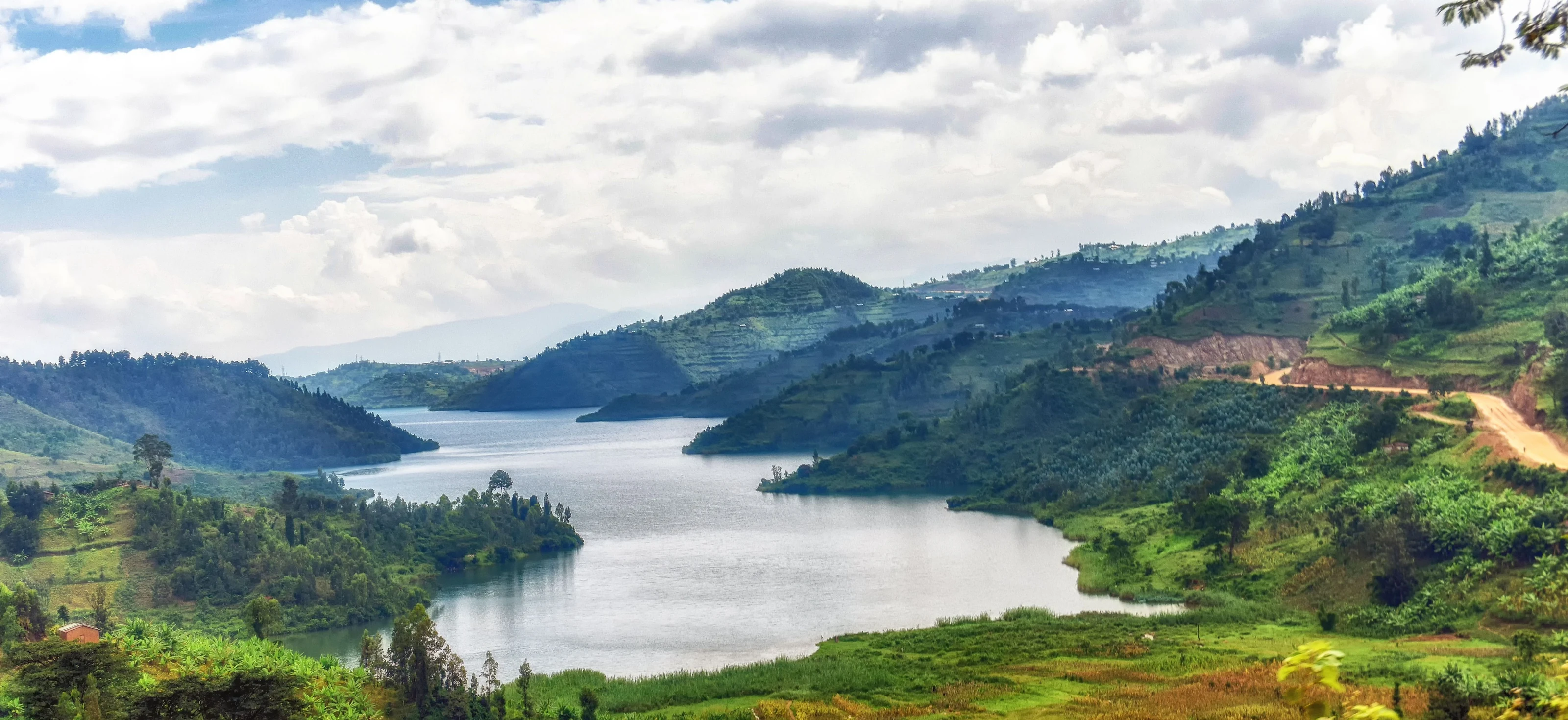 Calm lake between green terraced hills under cloudy sky