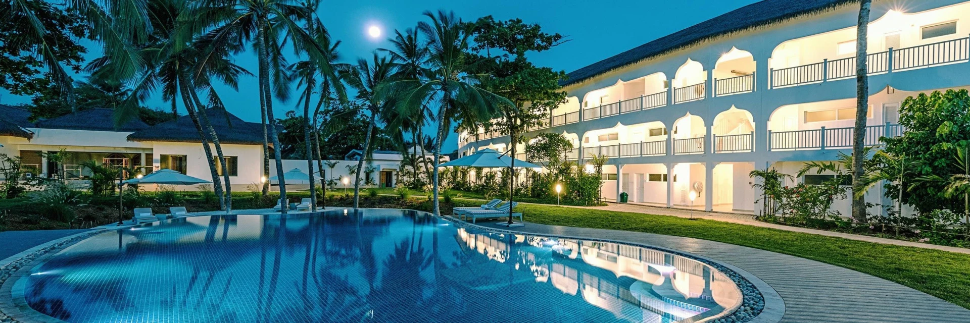 White colonial-style hotel and swimming pool beneath palms at Hemingways Watamu