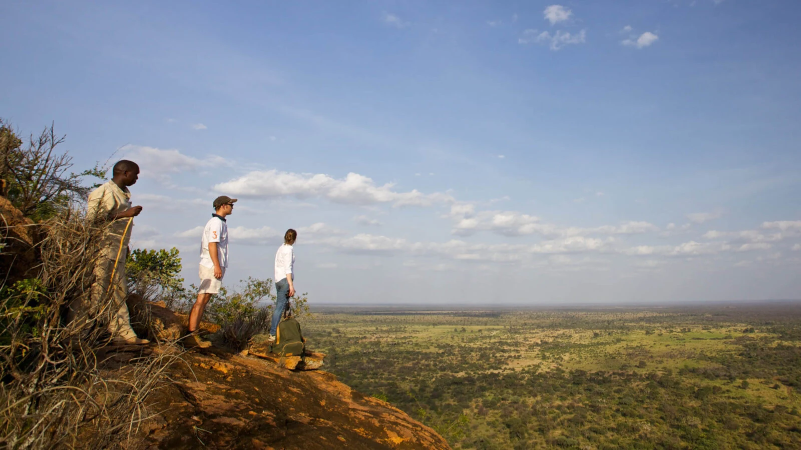 Guide and two guests on a hilltop looking over open plains