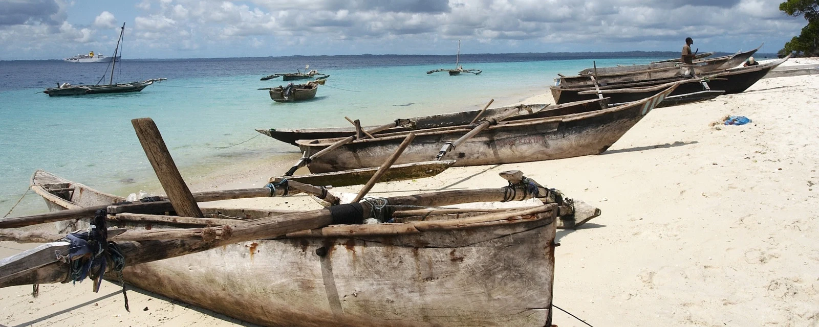 Wooden outrigger boats pulled up on a white beach