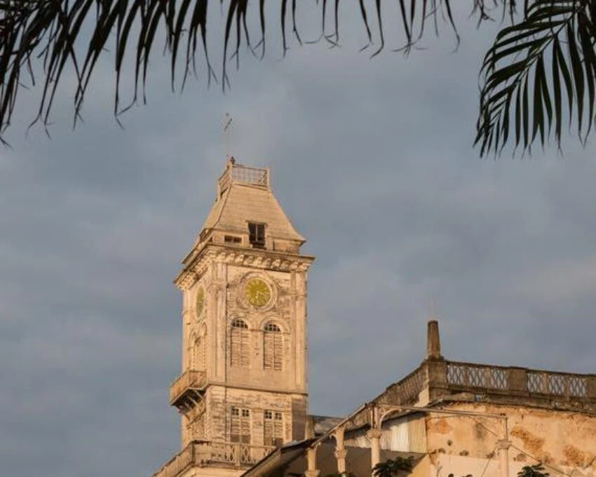 The House of Wonders clock tower in Stone Town, framed by palm fronds