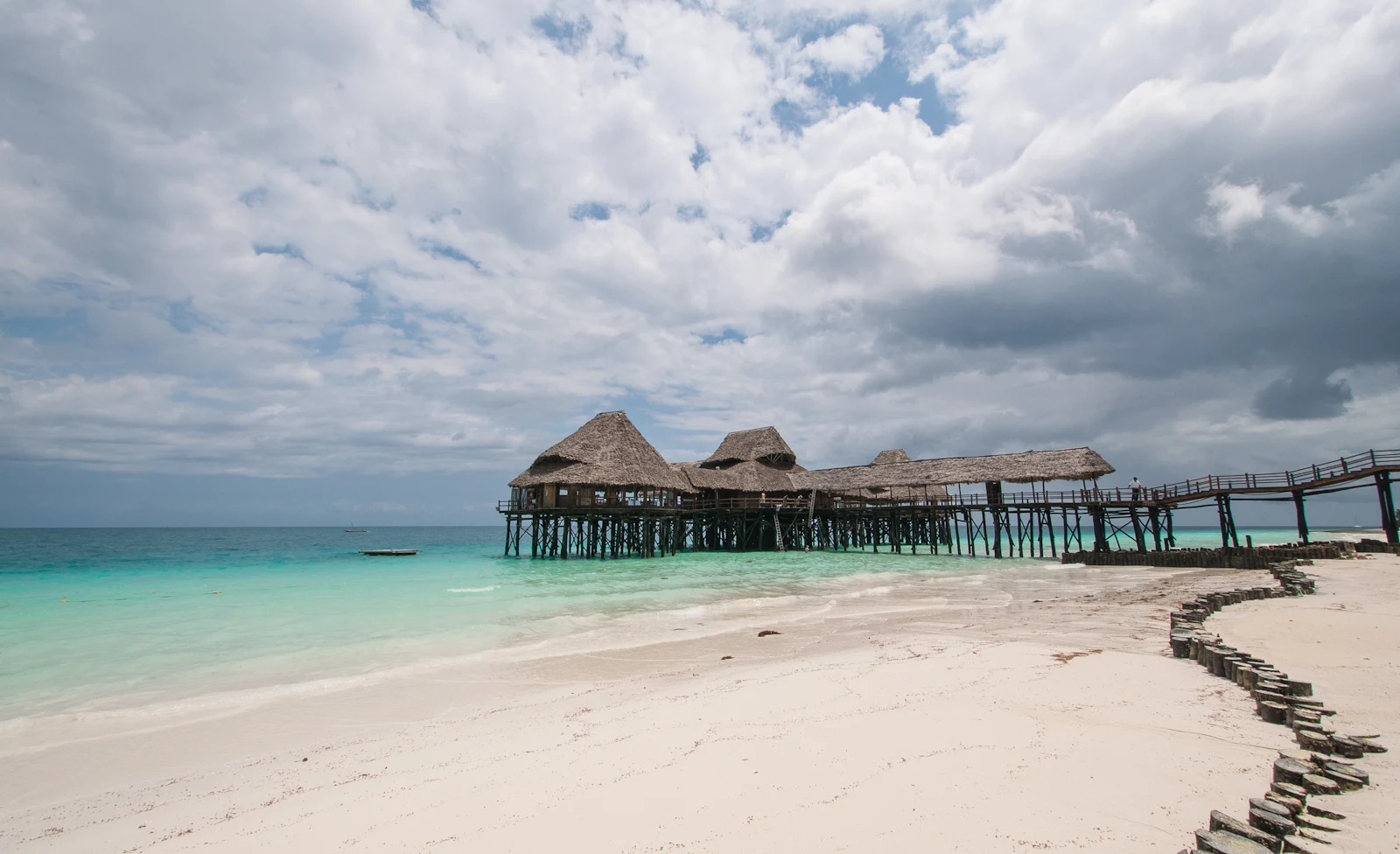 Kendwa beach with a wooden pier and thatched huts over turquoise water