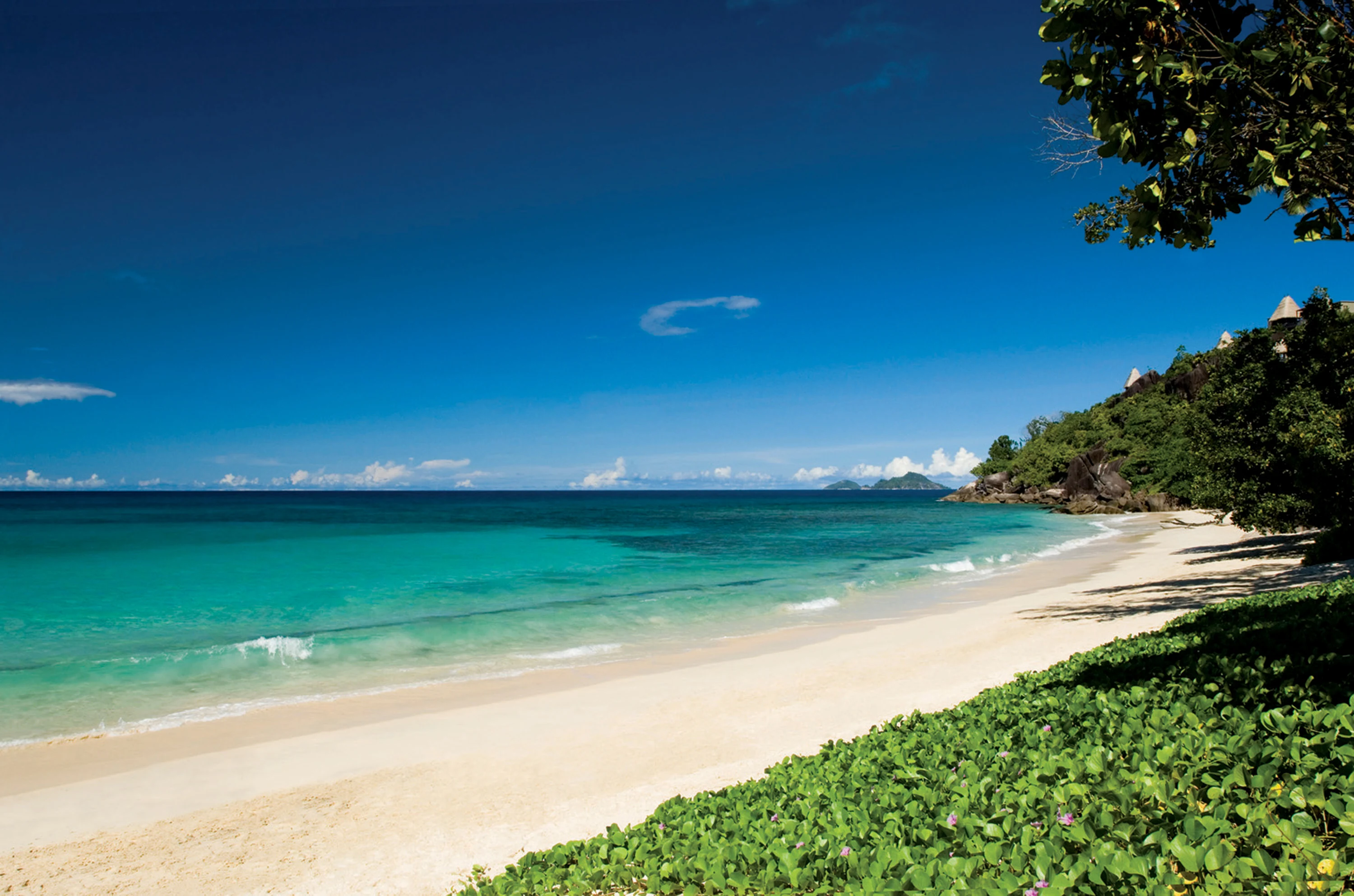 A quiet white beach and clear turquoise sea under a deep blue sky