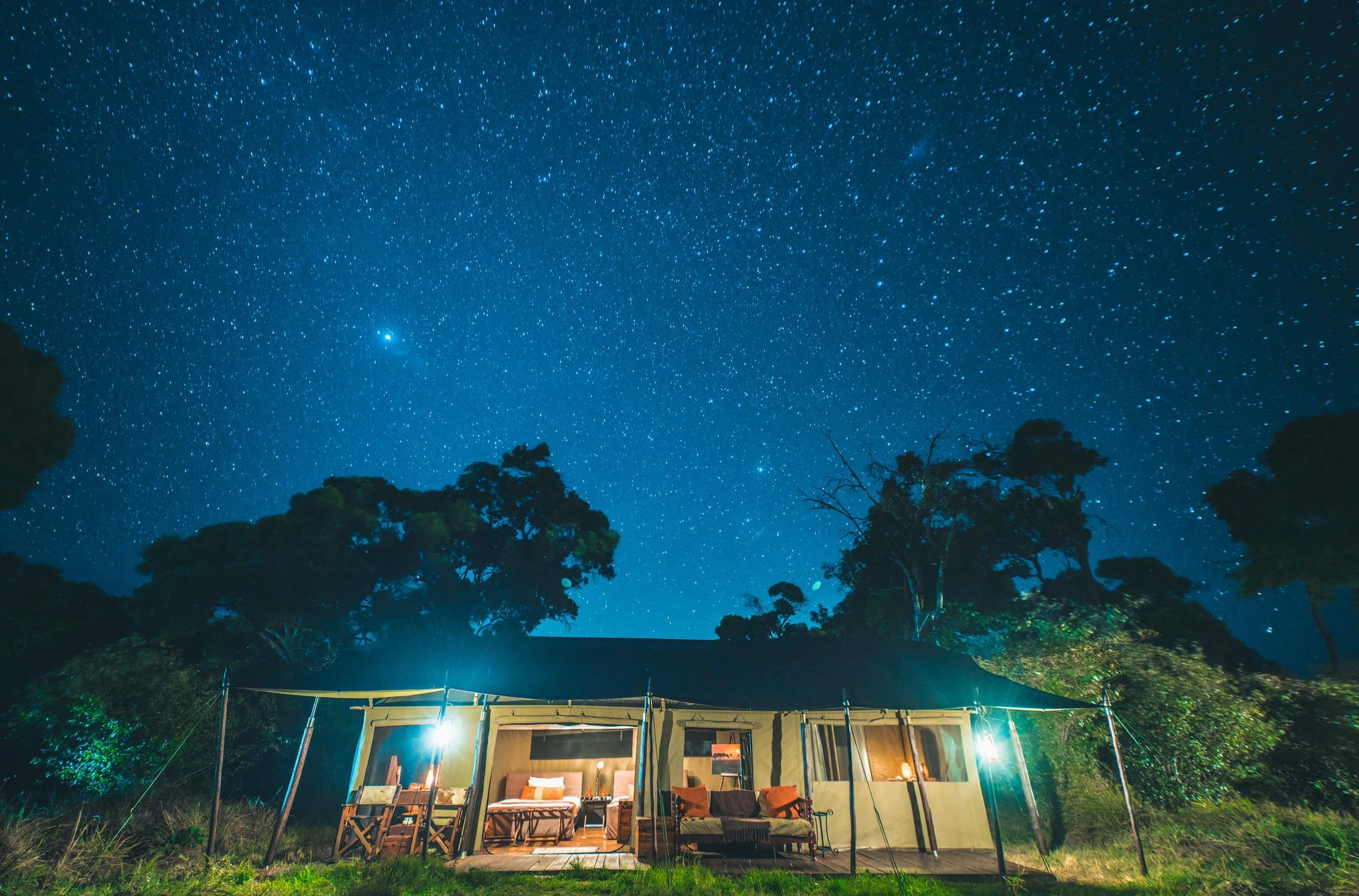 A lit safari tent beneath a sky full of stars