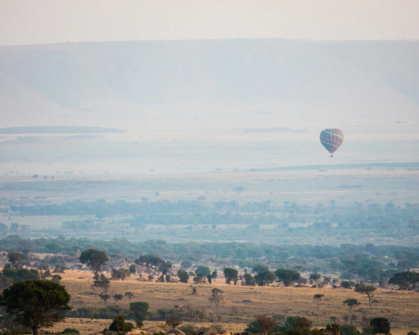 A hot-air balloon far off over hazy savanna in the central Serengeti