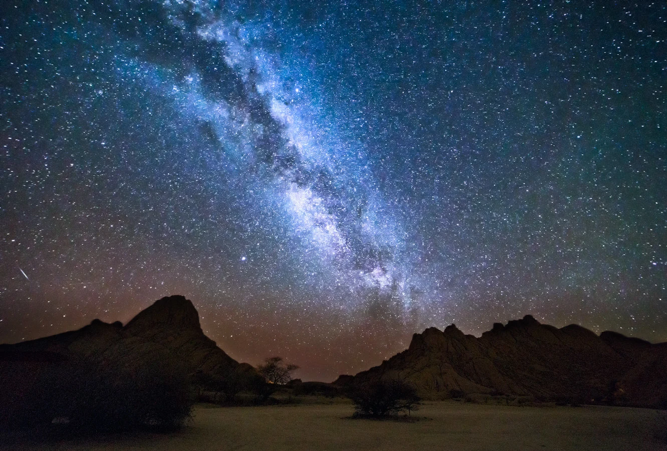 The Milky Way rising above dark rocky peaks in a starry night sky