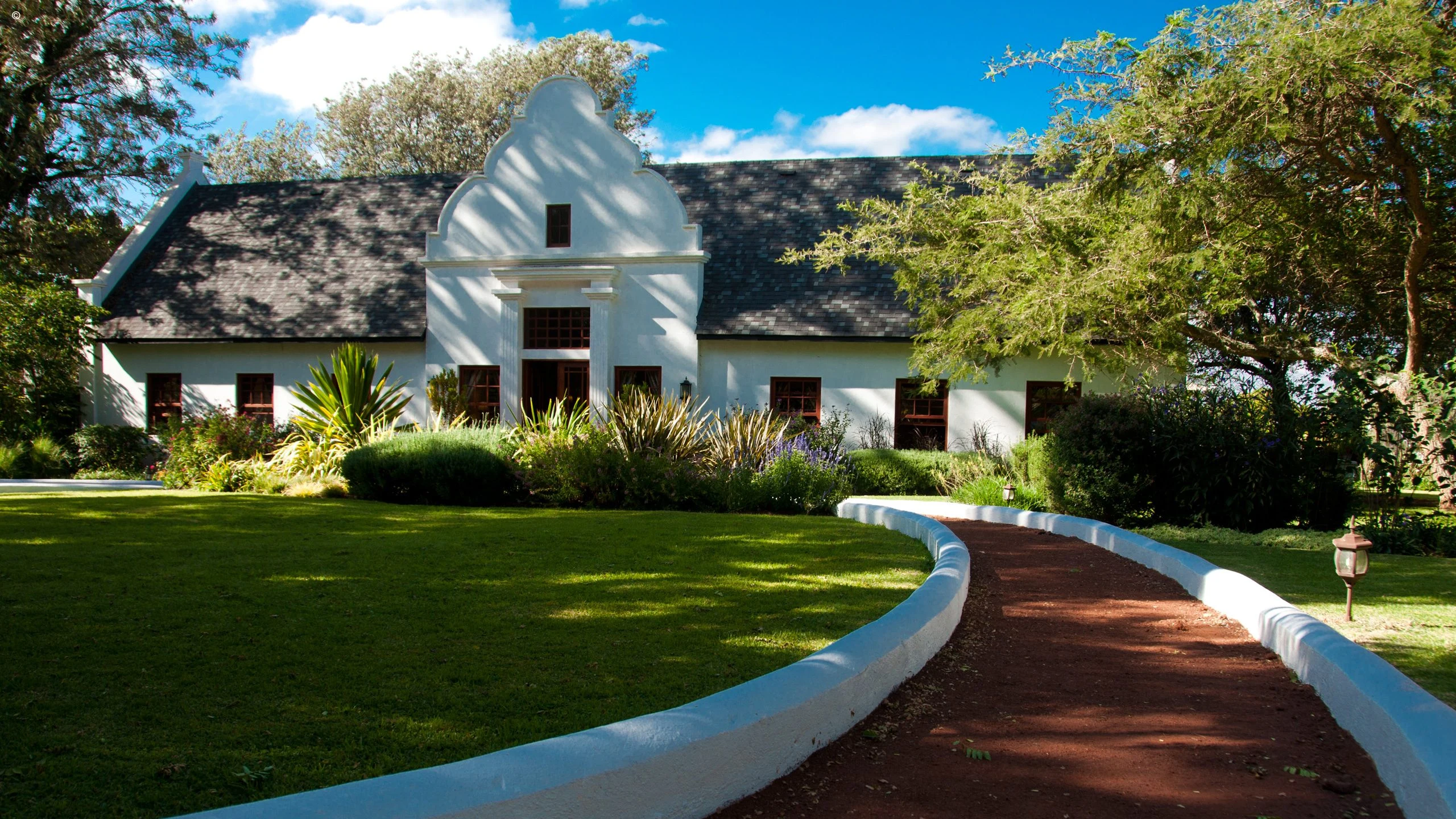 White lodge beyond garden path at The Manor at Ngorongoro