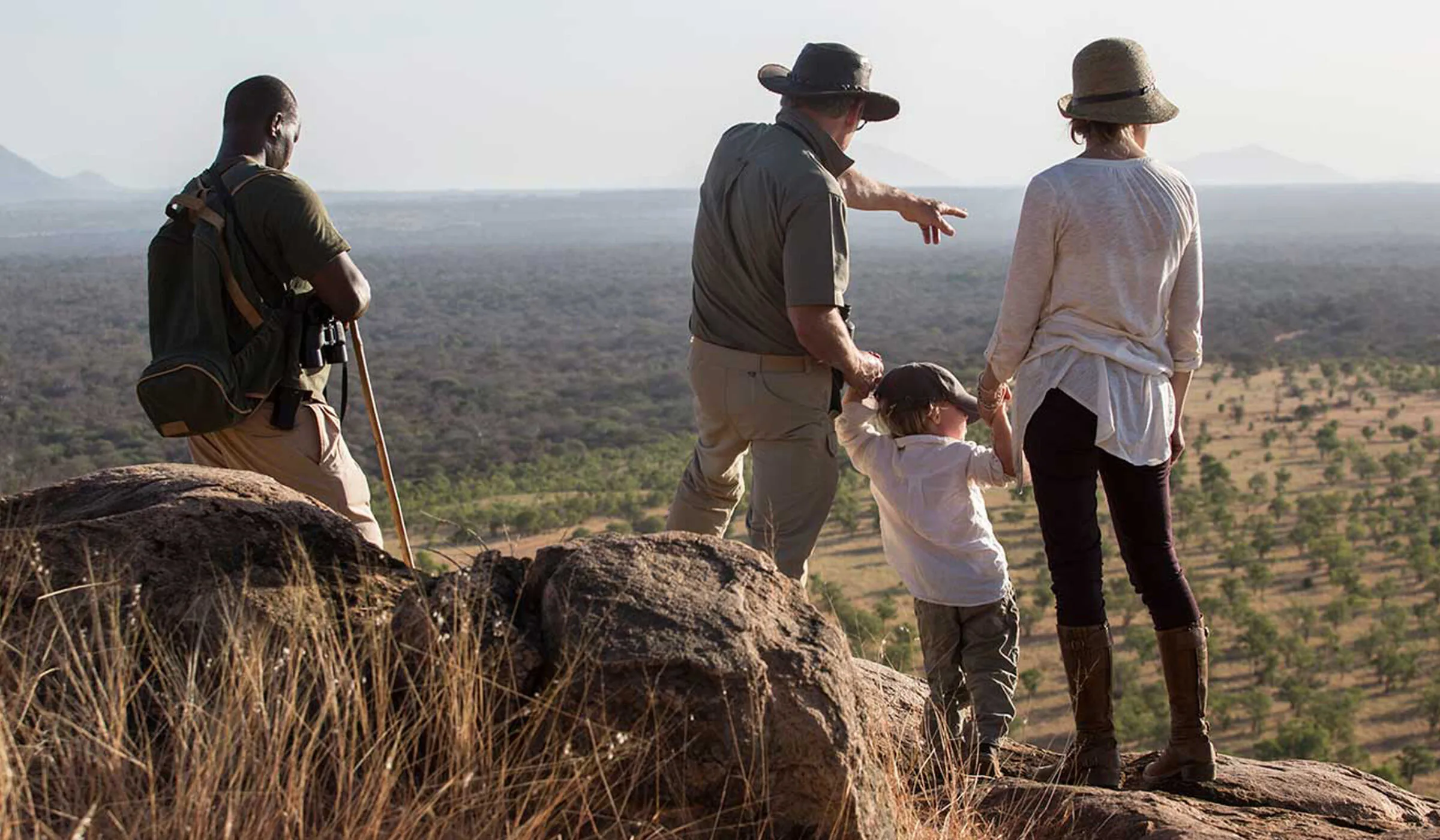 A family with their guide looking out over the plains from a rocky viewpoint