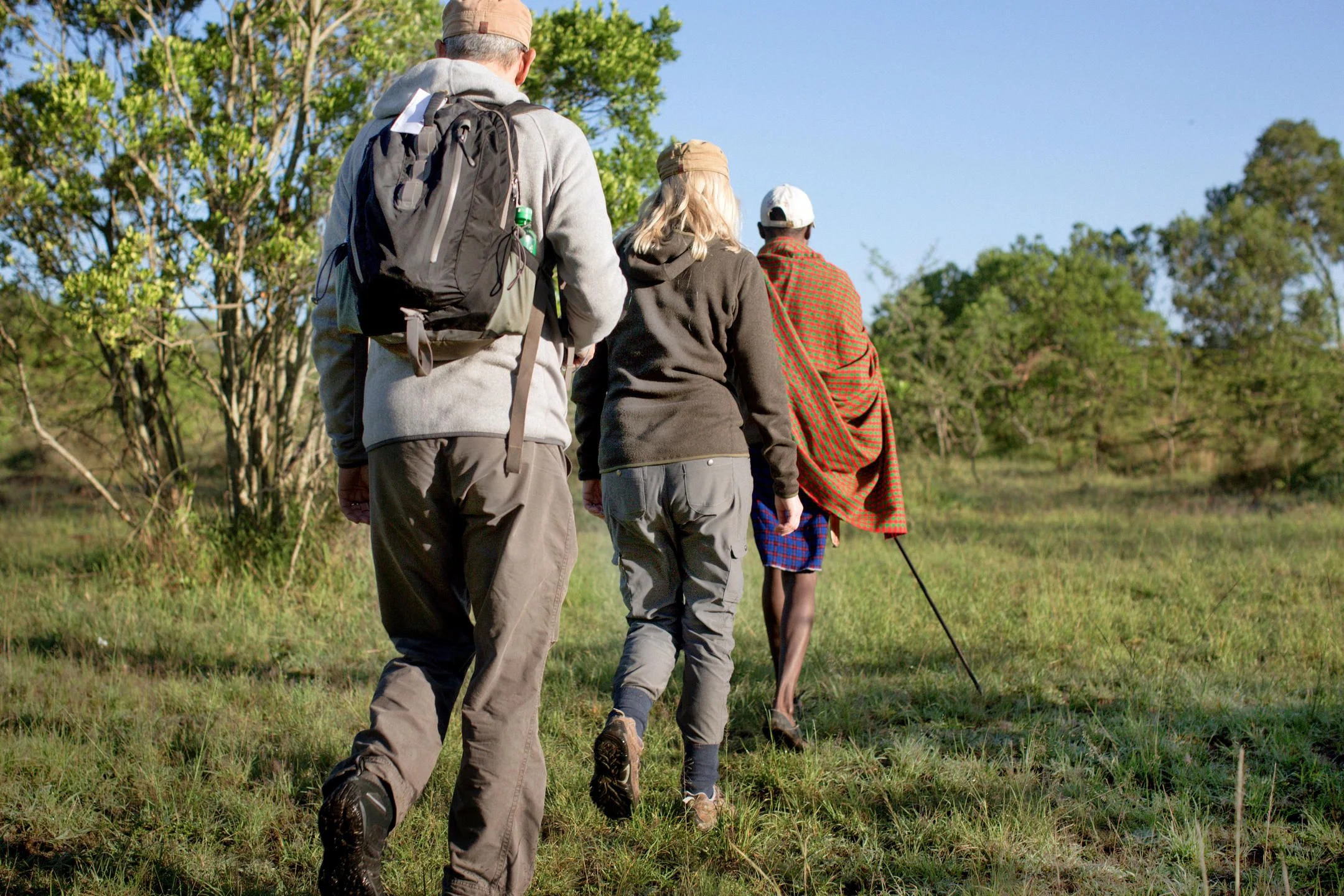 Walkers with a Maasai guide on a forest-edge trail in Mara North