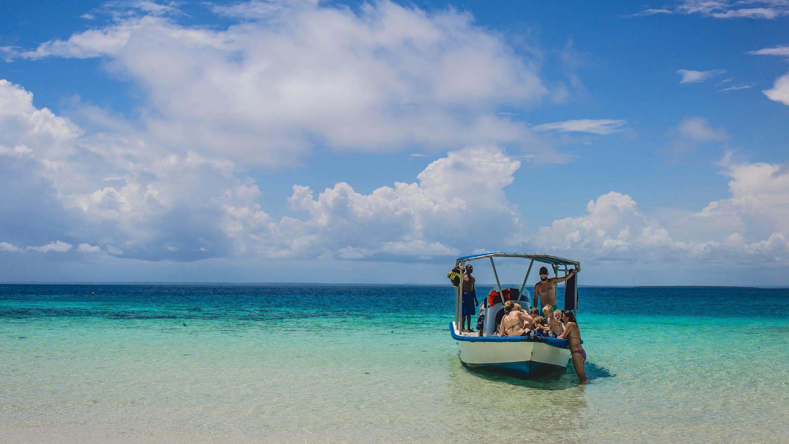 Small boat with swimmers in shallow turquoise water off Galu Beach