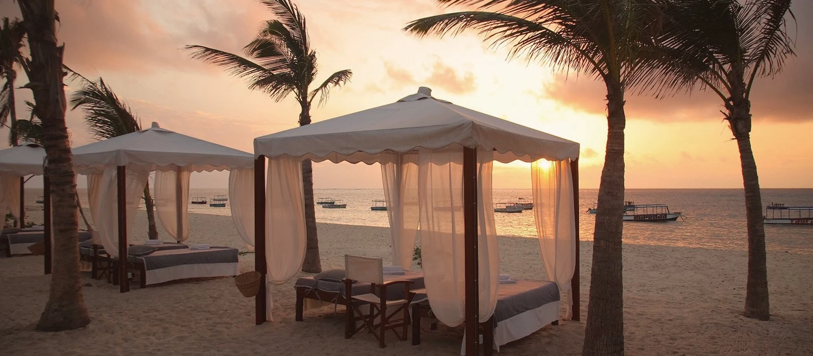 Beach cabanas under palms at sunset on Kenya's coast