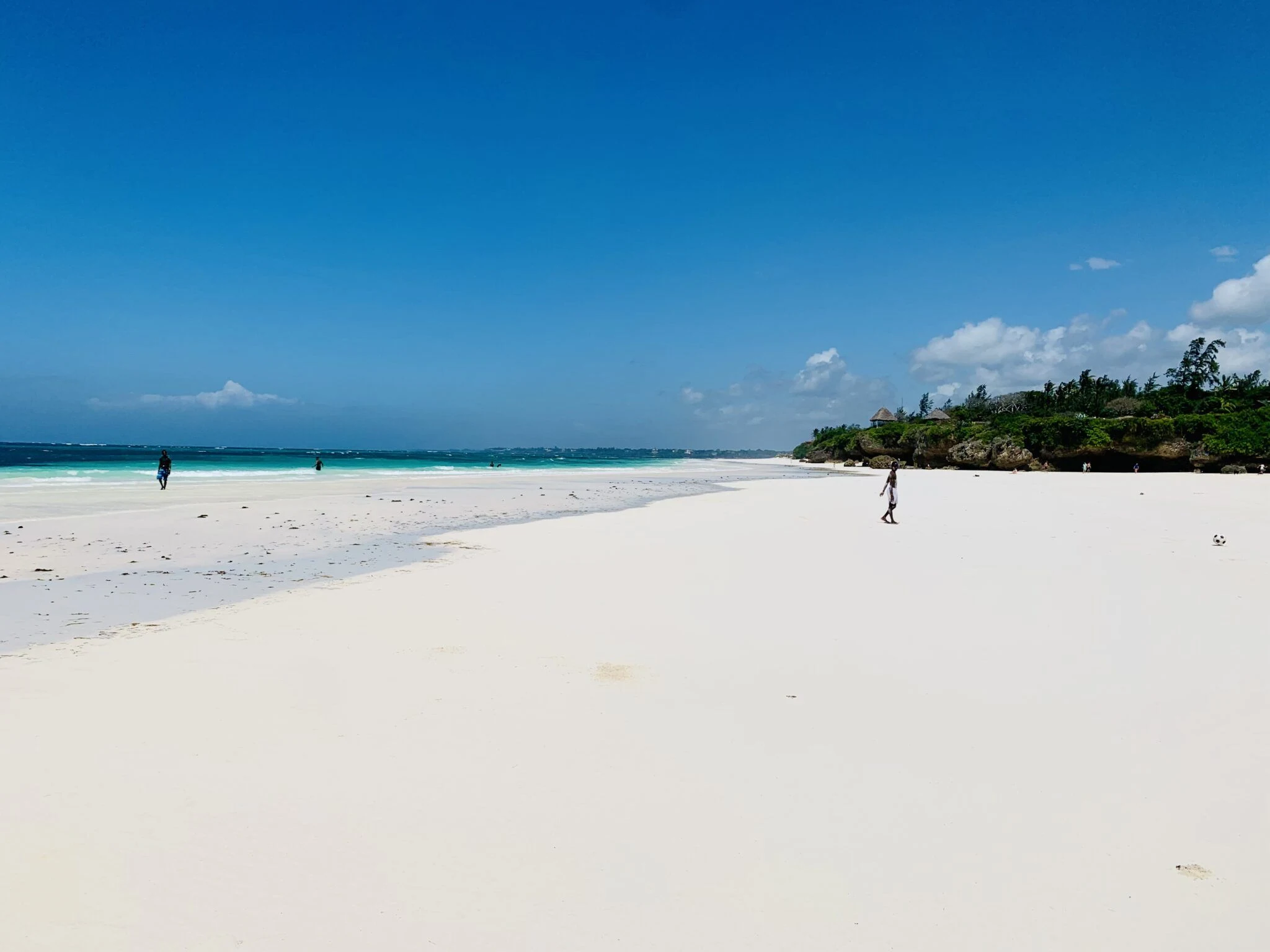 Empty white-sand beach with turquoise sea and a palm-topped headland at Kilifi
