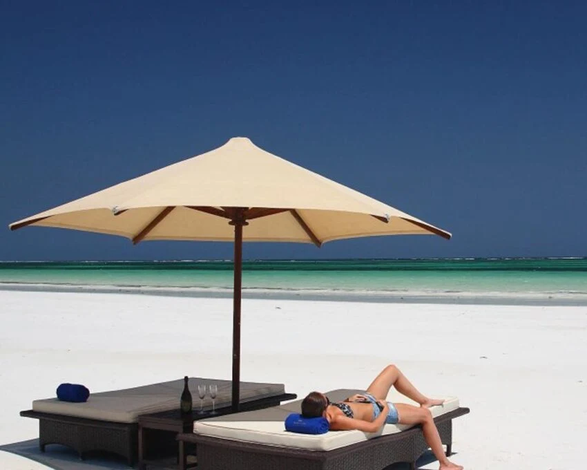 Beach umbrella and loungers on white sand with a woman lying down