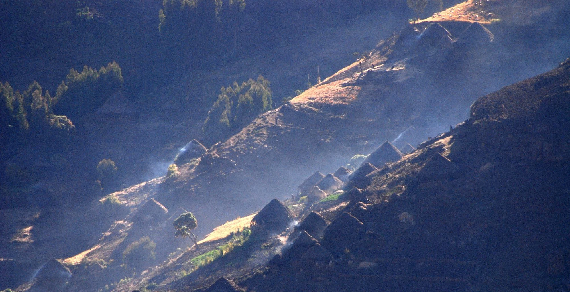 Morning light falls on thatched village houses on a Simien hillside.