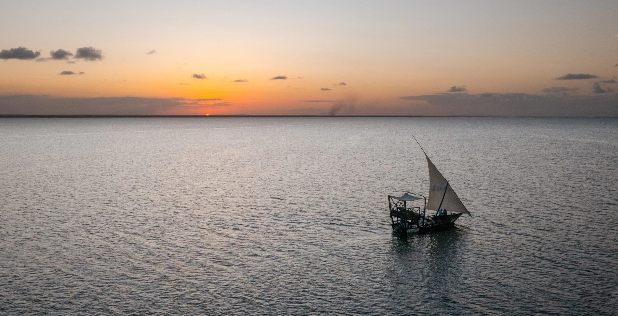 Dhow sailing on a calm sea at sunset