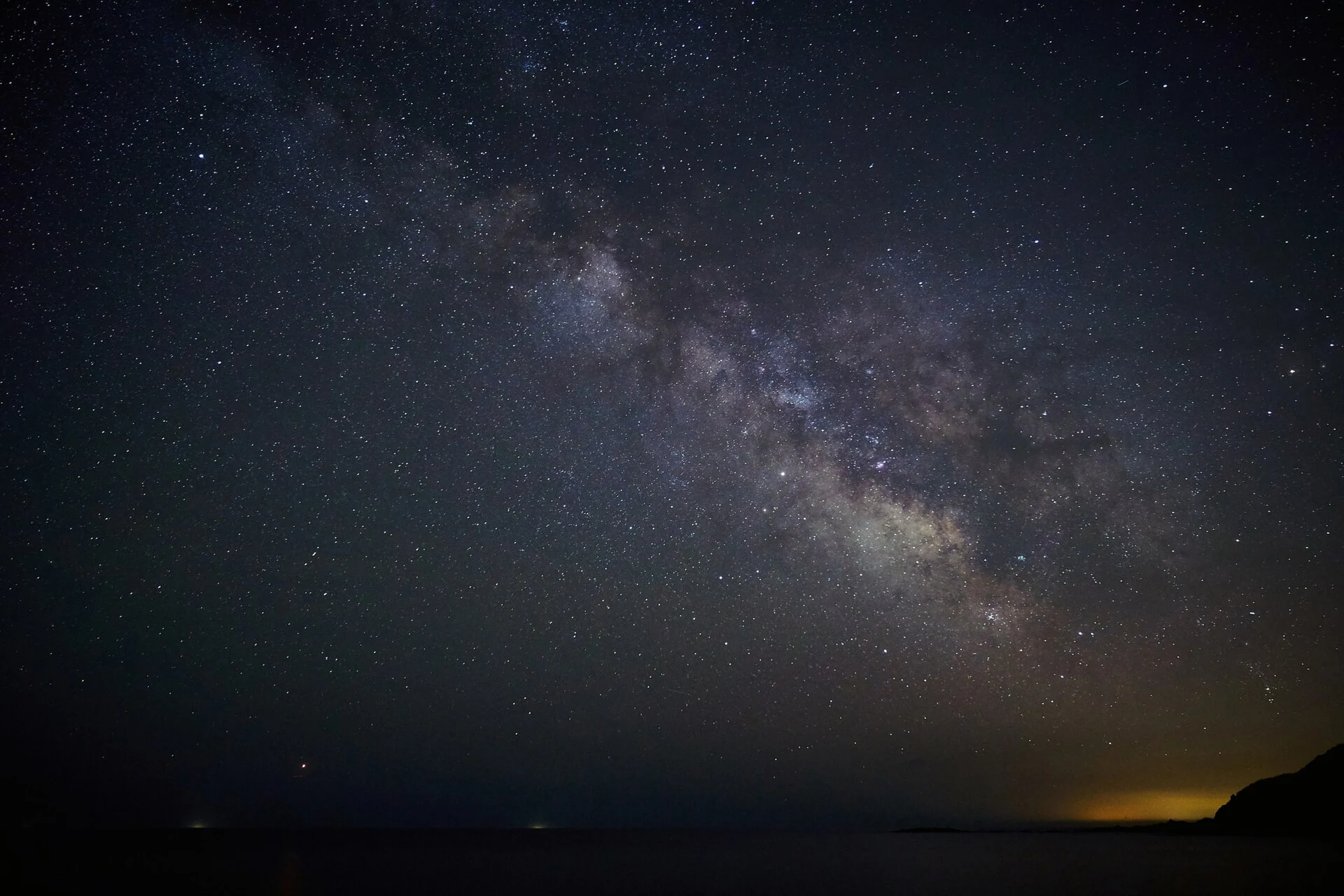 The Milky Way rising above a dark sea horizon at night
