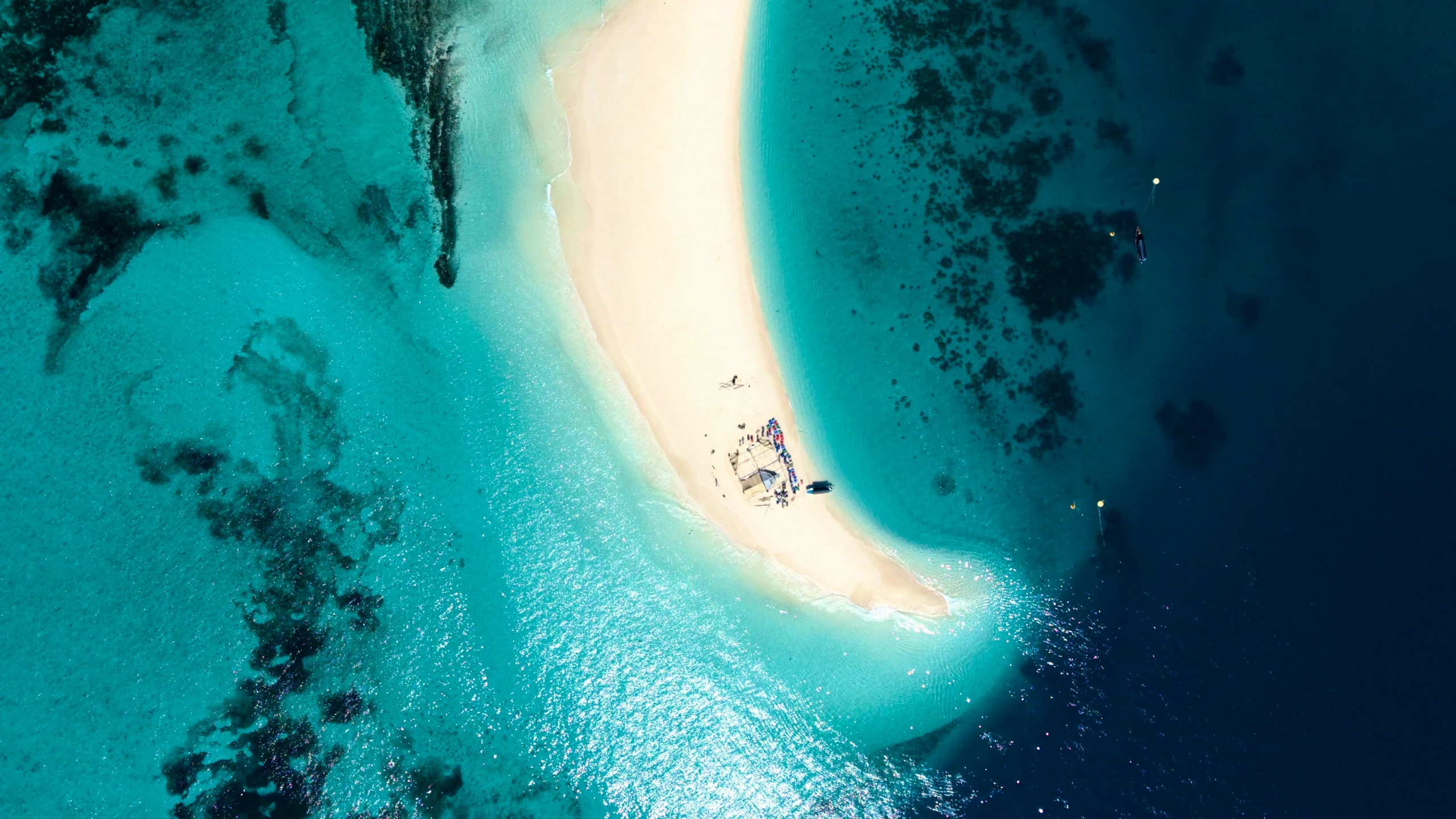 Drone view of a curved white sandbar and small boats in turquoise water off Zanzibar, Tanzania