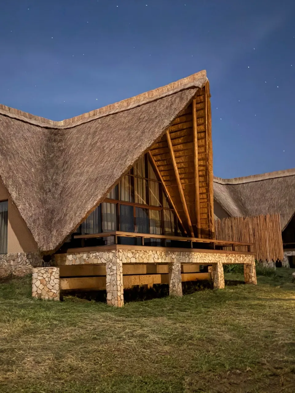 Exterior view of the Family Cottage at Entikko Safari Lodge with thatched A-frame roof at dusk
