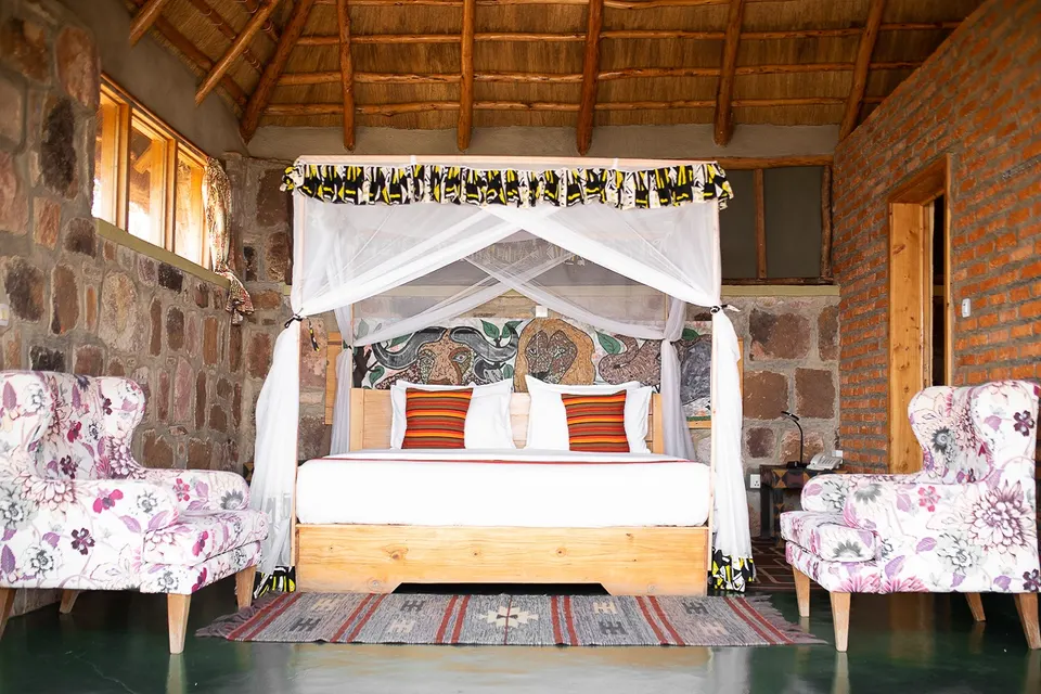 Akagera Rhino Lodge stone-walled bedroom beneath thatch