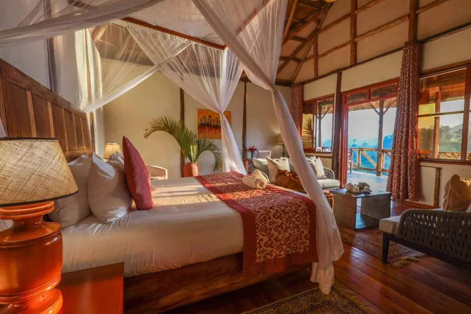 Crater Safari Lodge timber chalet bedroom with netted beds and balcony doorway
