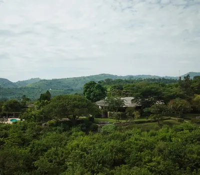 Kyambura Gorge Lodge buildings within a green hillside landscape; public inline preview