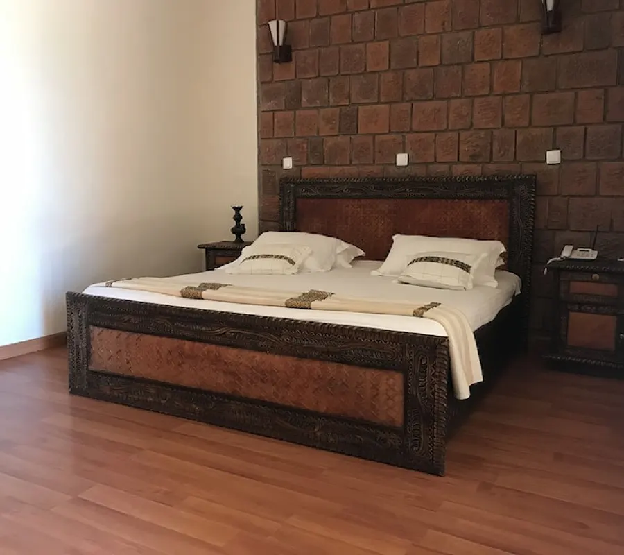 Lalibela Lodge bedroom with wooden bed and stone accent wall
