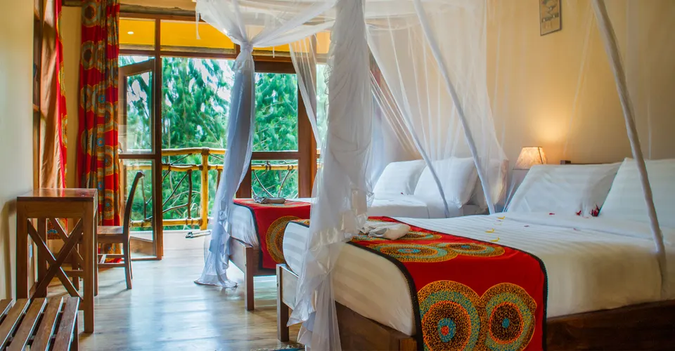 Ichumbi Gorilla Lodge bedroom with netted bed and balcony doorway