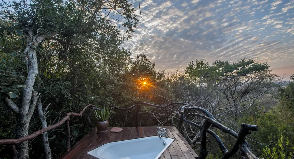 Outdoor bathtub on a wooden chalet veranda at Mbalageti