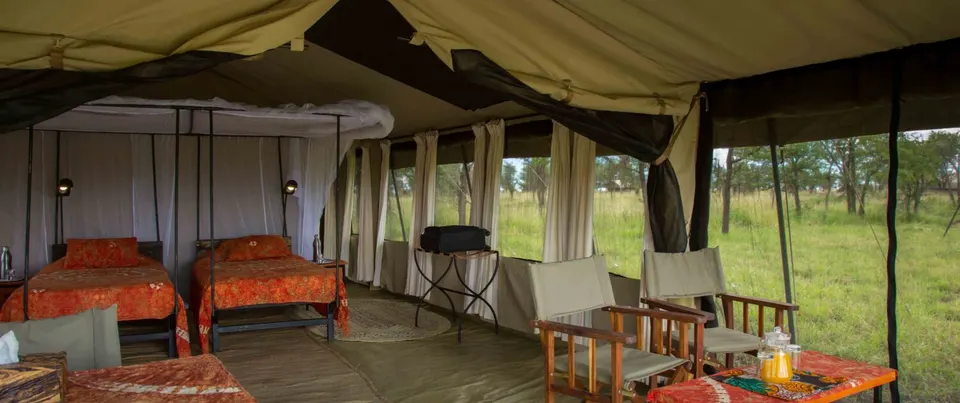 Screened tent sitting area with beds behind