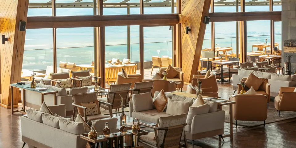 Safari lodge lounge with panoramic views, comfortable seating, and wood design.